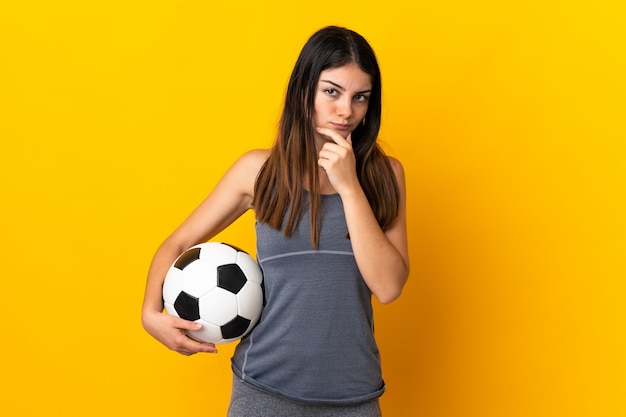 Mujer joven futbolista aislada en pensamiento amarillo