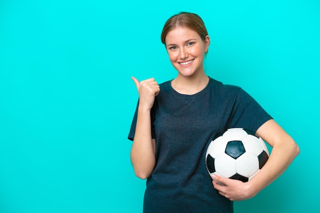 Mujer joven futbolista aislada sobre fondo azul apuntando hacia el lado para presentar un producto