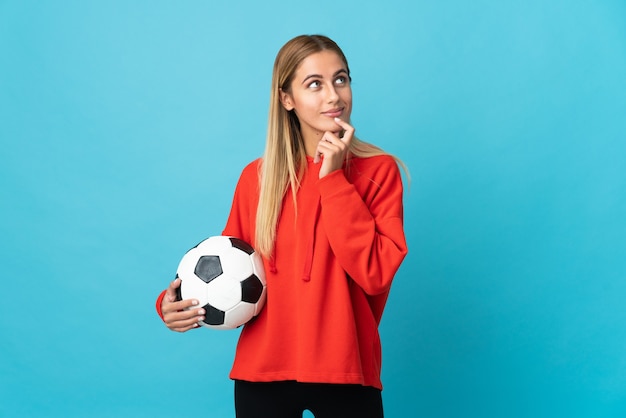 Mujer joven futbolista en azul y mirando hacia arriba