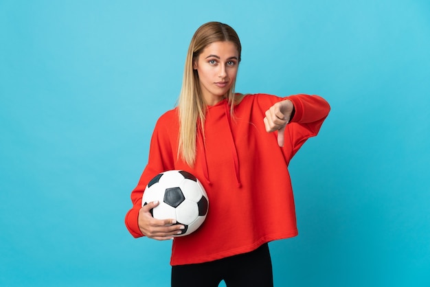 Mujer joven futbolista en azul mostrando el pulgar hacia abajo con expresión negativa