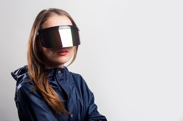 Mujer joven del futuro con gafas de realidad virtual y una chaqueta azul sobre un fondo claro.