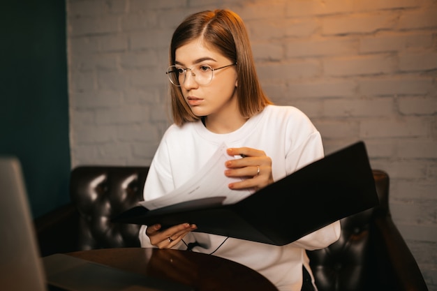 Mujer joven con gafas escribiendo y usando una computadora portátil, tutor brinda lecciones de idiomas en línea, aprendizaje a distancia, capacitaciones