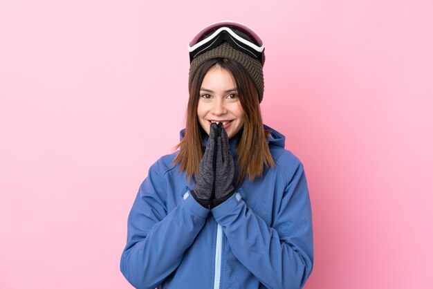 Mujer joven con gafas de esquí sobre pared rosa