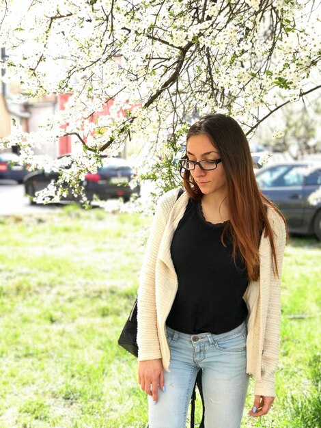 Foto mujer joven con gafas de pie en el parque.