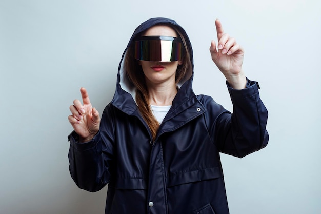 Mujer joven en gafas de realidad virtual presionando los dedos en una pantalla táctil sobre un fondo claro