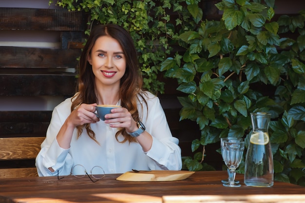 Mujer joven con gafas se sienta en una mesa en un café