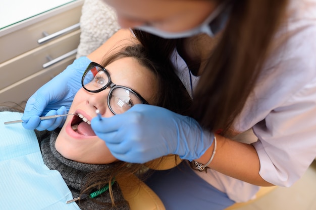 Mujer joven con gafas en sillón dental