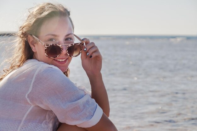 Mujer joven en gafas de sol con cabello en desarrollo sonriendo Concepto de descanso de verano juvenil