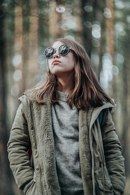 Mujer joven con gafas de sol con chaqueta de pie en invierno