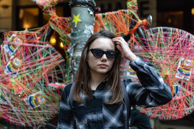 Mujer joven con gafas de sol contra la decoración multicolor