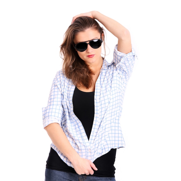 Una mujer joven con gafas de sol posando sobre fondo blanco.