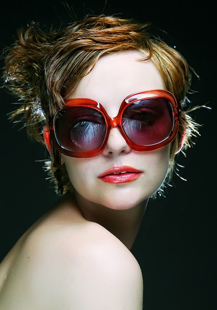 Mujer joven con gafas de sol sobre fondo negro