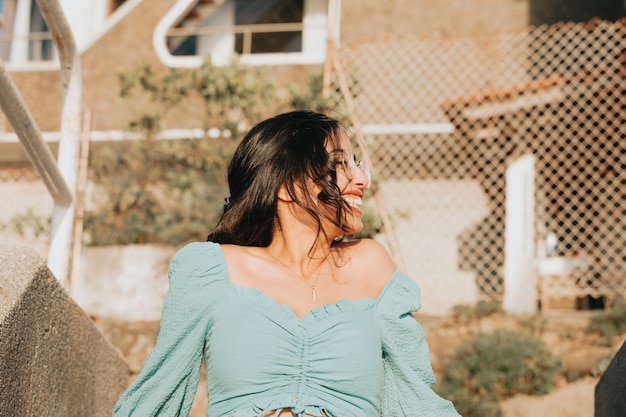 Mujer joven con gafas sonriendo a la cámara durante un día super soleado