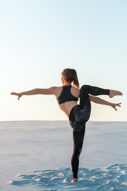 Mujer joven gimnasta profesional danza al aire libre - playa de arena. Concepto de fitness, deporte, personas y estilo de vida.