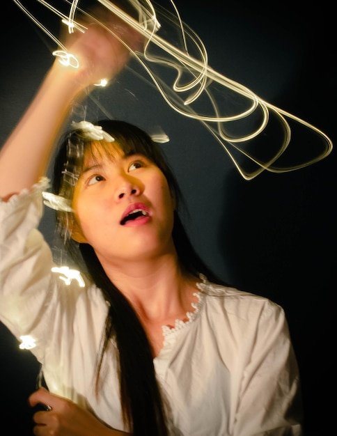 Foto mujer joven girando equipos de iluminación iluminados contra la pared