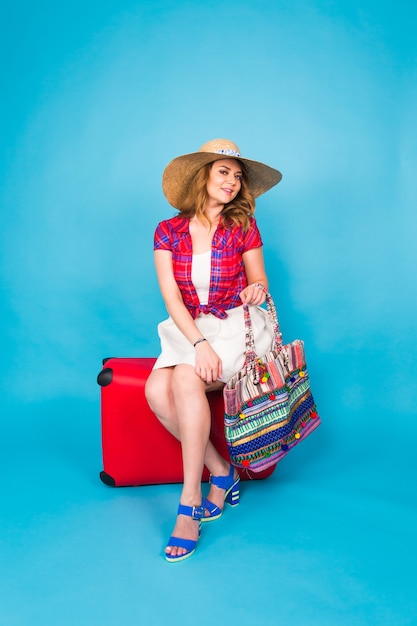 Mujer joven glamour con maleta roja. Concepto de viajes, vacaciones y personas.