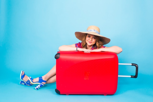 Mujer joven glamour con maleta roja. Concepto de viajes, vacaciones y personas.