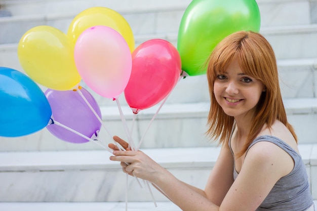 Mujer joven con globos de colores en el parque