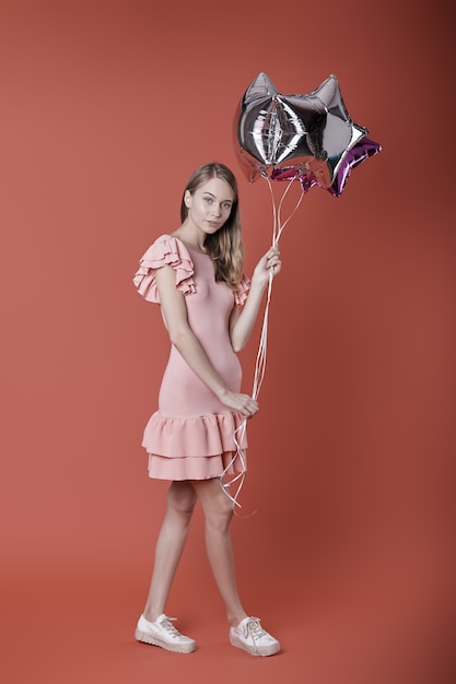 Mujer joven con globos de estrellas en la pared roja