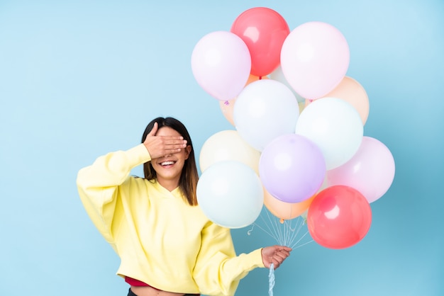 Mujer joven con globos sobre pared aislada