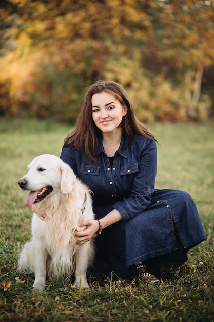 Mujer joven con un golden retriever en un hermoso parque de otoño