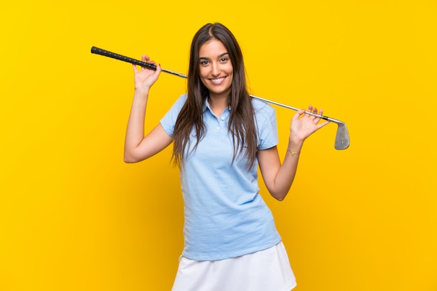 Mujer joven golfista sobre pared amarilla aislada