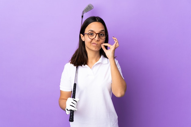 Mujer joven golfista sobre pared colorida mostrando un signo de gesto de silencio