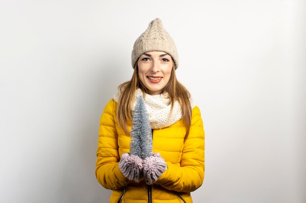 Mujer joven en un gorro y mitones sonríe aislado