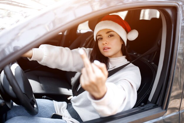 Foto mujer joven con gorro de papá noel conduciendo su coche