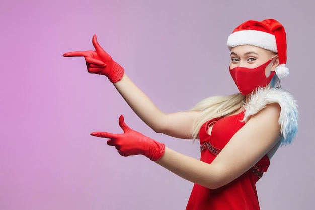 Mujer joven con un gorro de Papá Noel y mascarilla para Navidad