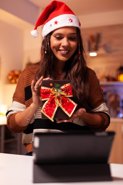 Mujer joven con gorro de Papá Noel con tecnología de videollamada