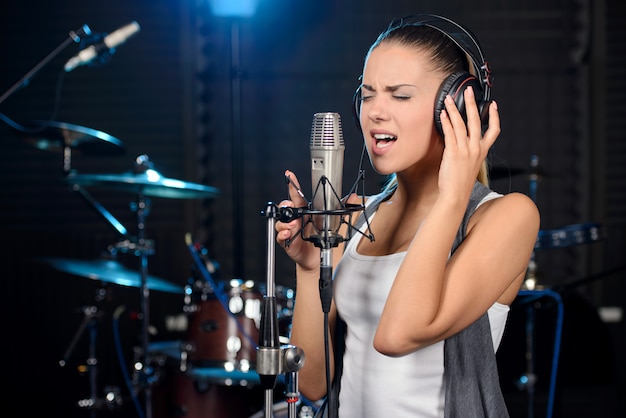 Mujer joven grabando una canción en un estudio profesional