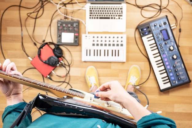 Foto mujer joven grabando guitarra eléctrica en la sala de ensayo, tiro del punto de vista. vista superior de la productora en casa estudio tocando la guitarra e instrumentos electrónicos.