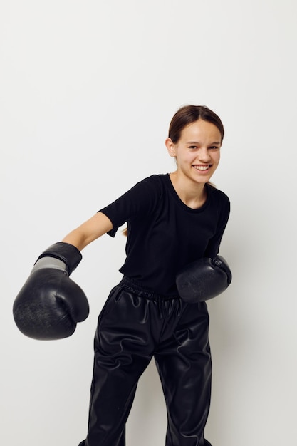 Mujer joven en guantes de boxeo en pantalones negros y una camiseta de fondo aislado