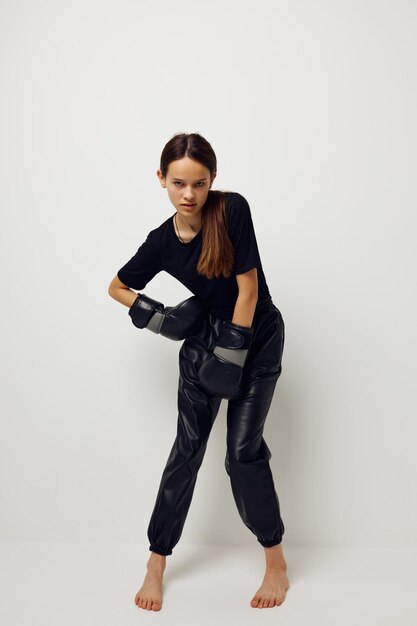 Mujer joven en guantes de boxeo uniformes deportivos negros posando estilo de vida inalterado