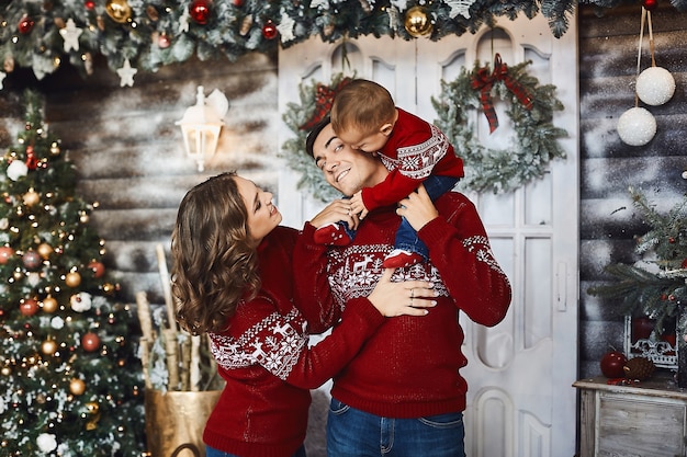 Mujer joven y guapo con un bebé sobre sus hombros posando en un interior de Navidad.