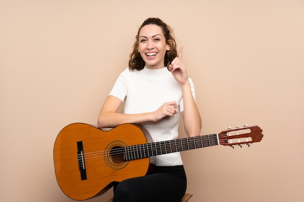 Mujer joven con guitarra apuntando una gran idea