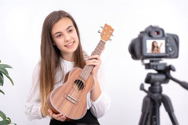 Mujer joven con guitarra creando contenido en línea sobre fondo blanco con espacio de copia