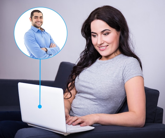 Mujer joven hablando con el hombre a través de video chat en la computadora portátil