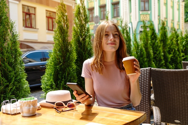 Mujer joven hablando por teléfono en un café en una terraza de verano