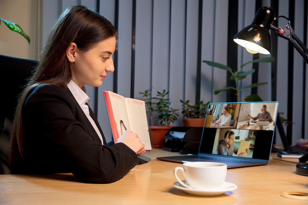 Mujer joven hablando, trabajando durante una videoconferencia con colegas en casa