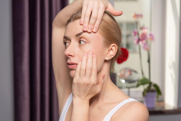 Una mujer joven hace un automasaje facial por el efecto de elevación y rejuvenecimiento.