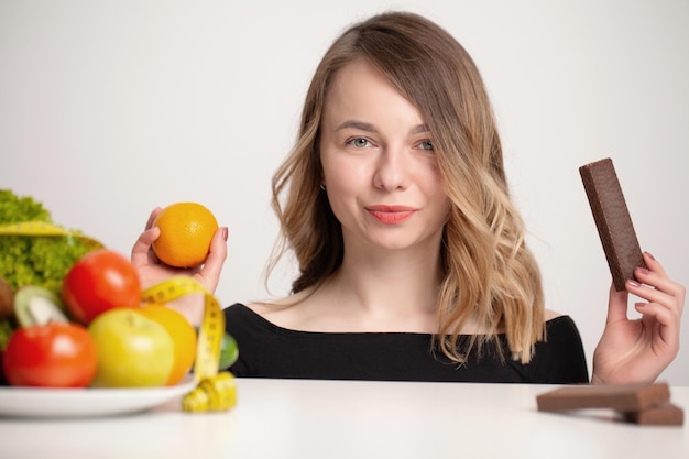 Mujer joven hace una elección entre alimentos saludables y no saludables.