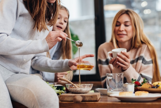 Mujer joven hace granola y miel en casa en la cocina.