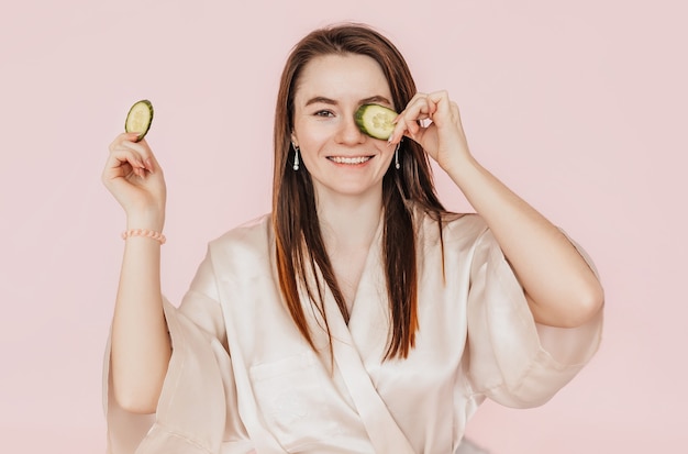 Foto mujer joven hace mascarilla de belleza facial casera con rodajas de pepino