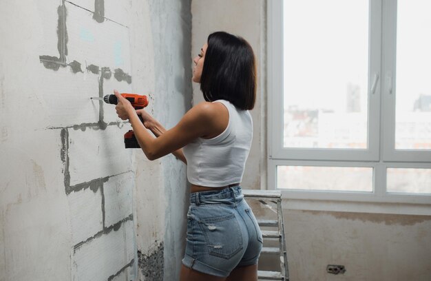 Una mujer joven hace renovaciones de apartamentos concepto de renovación de apartamentos mujer fuerte independiente alta ...