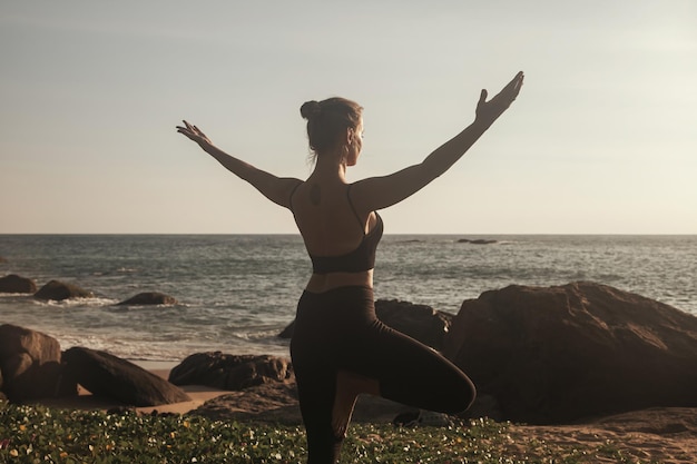 Mujer joven hace yoga para un estilo de vida saludable en la playa del mar