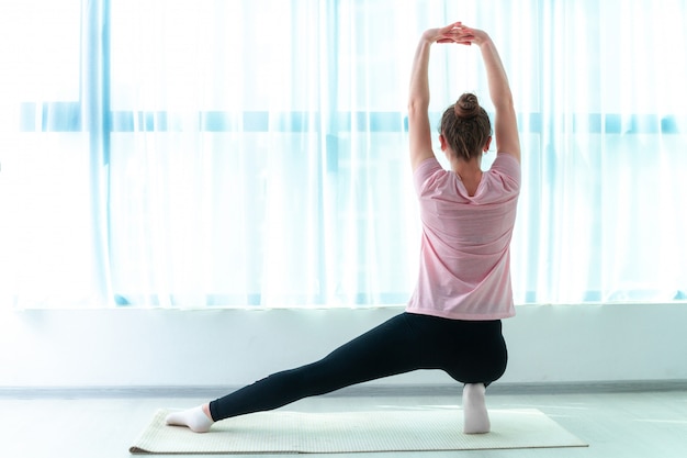 Mujer joven hacer ejercicios de entrenamiento muscular y fitness en estera de yoga en casa. Pierde peso y mantente en forma. Estilo de vida deportivo saludable