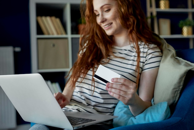 Mujer joven haciendo algunas compras a través de la computadora