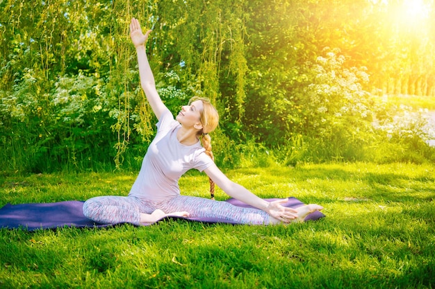 Mujer joven haciendo asanas de yoga en el parque niña ejercicio de estiramiento en posición de yoga feliz y saludable